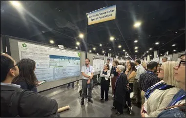 Conference attendees gathered around a research poster beneath a sign reading Antibiotic Stewardship: Special Populations.